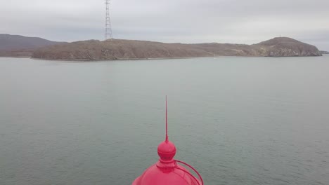 Ansicht-von-oben-rote-Dach-des-Leuchtturm-im-Meer-auf-Gebirgshintergrund