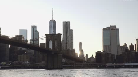 A-view-of-Lower-Manhattan-skyline-with-One-World-Trade-Center-filmed-from-the-boat-in-the-East-River-under-the-Brooklyn-Bridge-in-New-York,-United-States