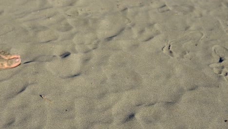 Ein-junger-Mann-zieht-ein-Herz-in-den-Sand.