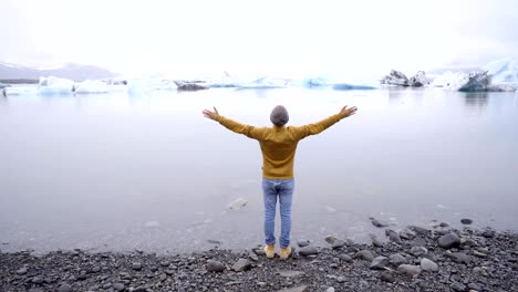 Hombre-joven-de-brazos-extendidos-en-la-laguna-de-glaciar-en-Islandia