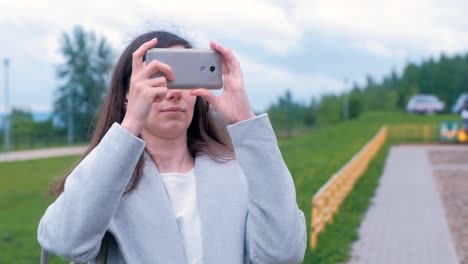 Young-woman-shoots-a-photo-and-video-on-a-mobile-phone-on-the-Playground.