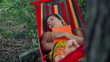 Young-woman-laying-down-on-hammock-and-reading-a-book