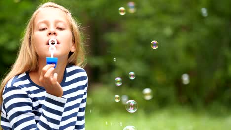 Niña-jugando-con-pompas-de-jabón-al-aire-libre.-Cámara-lenta.