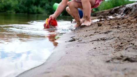 Blurred-childish-legs.-Children-playing-on-the-river-with-sand