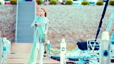 Young-beautiful-girl-stands-on-pier-with-fishing-net-and-posing-on-camera