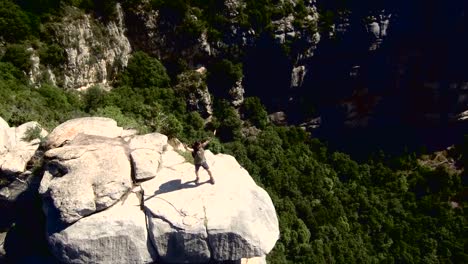 Caminante-con-mochila-de-pie-en-la-cima-de-una-montaña-aérea-4-K