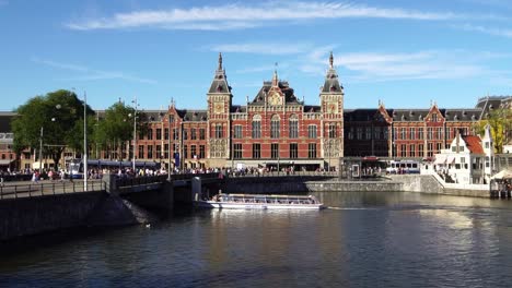 Tourist-boat-on-the-canal-center-in-front-of-Amsterdam-Central-station,-Europe.