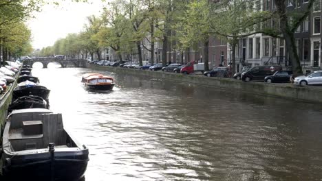 por-la-tarde-vista-del-sol-encendido-canal-y-un-barco-de-tour-en-Ámsterdam