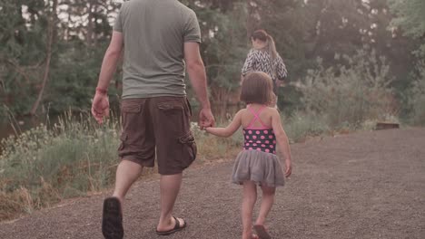 A-family-walking-down-a-park-trail-stop-to-look-at-the-water