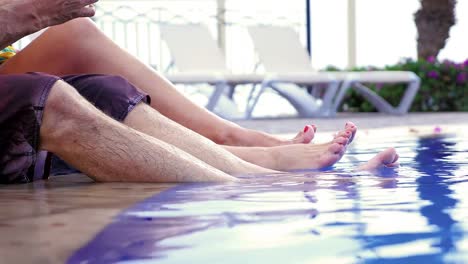 A-man's-and-a-woman's-feet-at-the-edge-of-a-pool