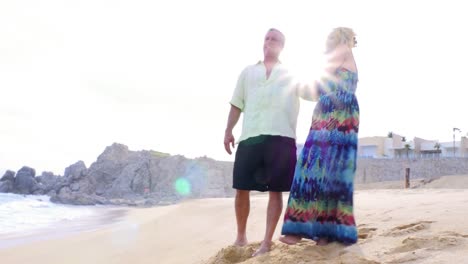 An-older-couple-holding-hands-and-looking-out-at-the-ocean