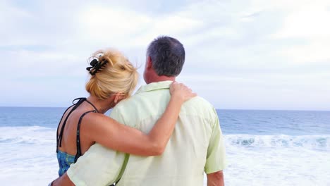 Close-up-of-an-older-couple-at-the-beach-with-their-arms-around-each-other-and-being-affectionate