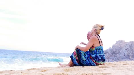 An-older-couple-sit-on-the-beach-and-watch-the-waves