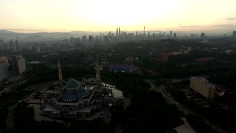 Luftbild-von-Sonnenaufgang-im-Federal-Moschee-Kuala-Lumpur-mit-Blick-auf-die-Skyline-der-Stadt-im-Hintergrund.