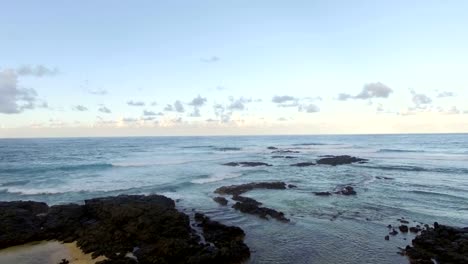 Flying-over-black-volcanic-stones-in-coastal-ocean-water