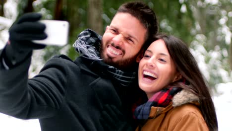 Couple-talking-and-taking-a-selfie-with-mobile-phone-on-a-winter-day