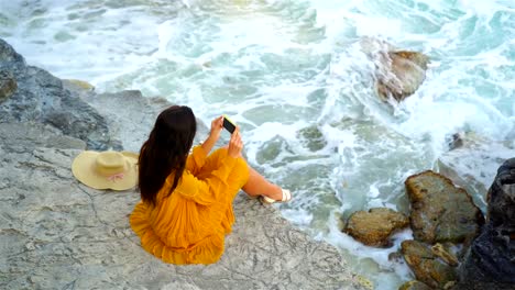 Junge-schöne-Frau-im-Kleid-auf-der-Klippe-über-dem-Meer.-Glückliches-Mädchen-am-Abend-am-Strand