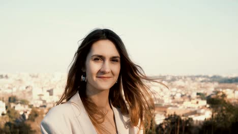 Portrait-of-young-beautiful-woman-against-the-panorama-of-Rome,-Italy.-Dreamy-female-looking-at-camera-and-smiling