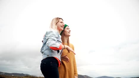 Two-tourists-female-standing-on-the-lava-field-in-Iceland-and-pointing-with-finger-on-something.-Happy-woman-talking