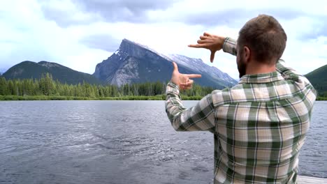 Young-man-standing-by-the-lake-framing-nature