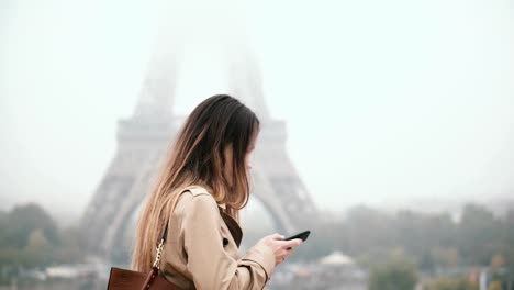 Junge-schöne-Frau-zu-Fuß-in-der-Innenstadt-und-am-Handy-sprechen.-Weibchen-in-der-Nähe-des-Eiffelturms-in-Paris,-Frankreich
