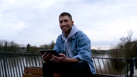 Portrait-of-a-Happy-Man-Reading-on-a-Digital-Tablet-in-Nature