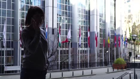 la-señora-es-caminando-y-hablando-por-el-teléfono-cerca-del-Parlamento-Europeo-en-Bruselas.-Bélgica.-cámara-lenta