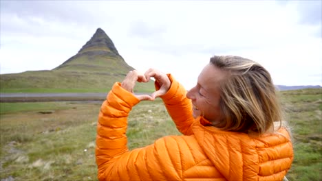 Mujer-joven-en-Islandia-que-marco-del-dedo-corazón-forma-a-la-famosa-montaña-de-Kirkjufell