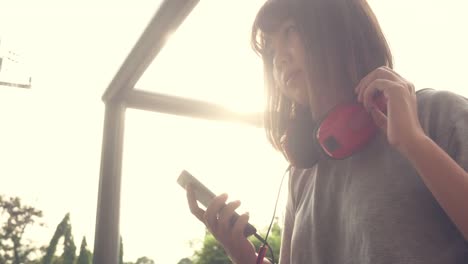 Hermosa-mujer-asiática-joven-escuchando-música-en-un-teléfono-inteligente-en-la-ciudad.-Mujer-asiática-joven-relajarse-escuchando-música-en-la-calle.