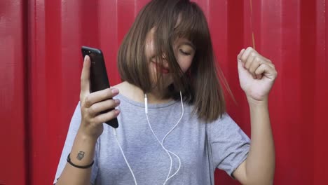 Schöne-junge-asiatische-Frau-anhören-von-Musik-auf-einem-Smartphone-in-der-Stadt.-Junge-asiatische-Frau,-entspannende-Musik-hören-auf-der-Straße.