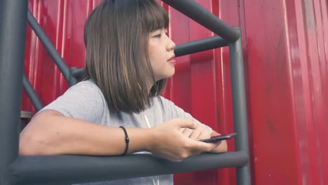 Hermosa-mujer-asiática-joven-escuchando-música-en-un-teléfono-inteligente-en-la-ciudad.-Mujer-asiática-joven-relajarse-escuchando-música-en-la-calle.