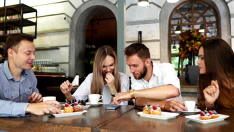 Dos-niñas-sentadas-en-un-café-mirando-el-teléfono-y-discutir-lo-que-vieron.-Un-chico-sube-y-muestra-una-imagen-divertida-en-su-teelphone