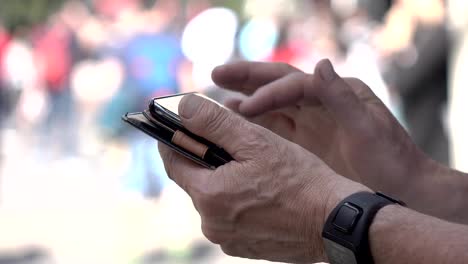 hands-of-a-man-using-a-smartphone-in-a-busy-city