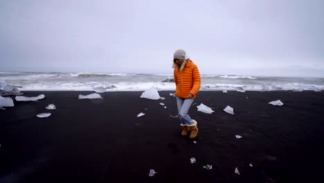 Junge-Frau-touristischen-weiblich-zu-Fuß-am-schwarzen-Sandstrand-am-Jökulsárlón-Diamond-beach