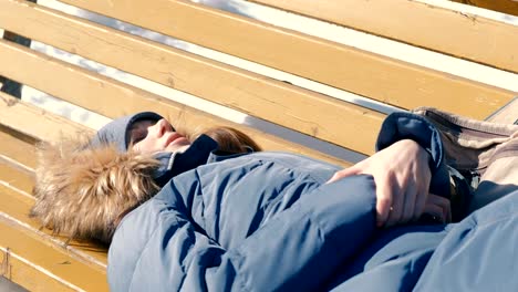 Müde-Mädchen-schläft-im-Park-auf-einer-Bank-im-Winter.