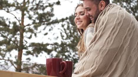 Cariñosa-pareja-abrazándose-en-el-porche-de-la-casa-del-bosque