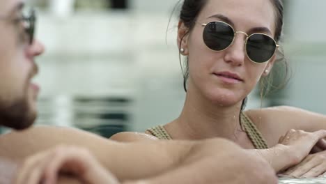 Couple-in-Sunglasses-Chatting-in-Swimming-Pool