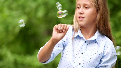 Niña-jugando-con-pompas-de-jabón-al-aire-libre.-Cámara-lenta.