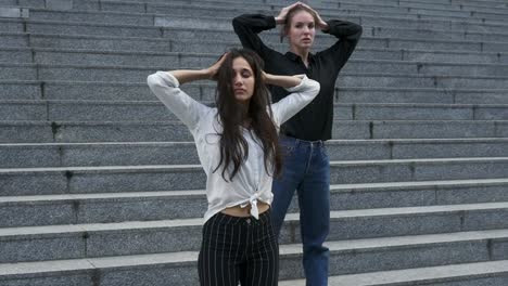 Dos-mujeres-jóvenes-en-la-escalera-Exterior-de-un-edificio-en-varias-Poses-de-baile