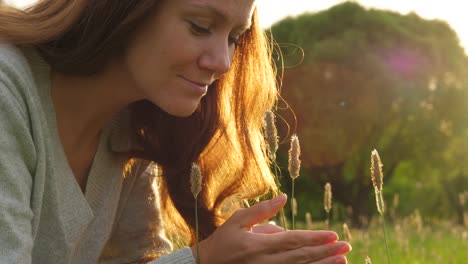 Portrait-of-woman-touching-grass-on-field-in-golden-sun-light