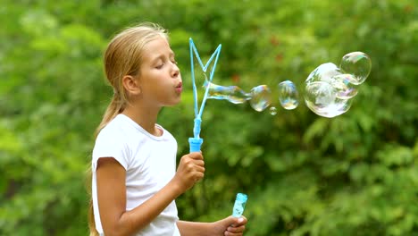 Little-girl-playing-with-soap-bubbles-outdoor.-Slow-motion.