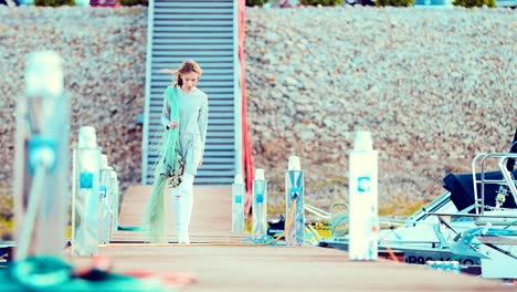 Young-beautiful-girl-walking-along-the-pier-with-a-fishing-net