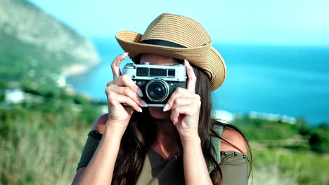 European-woman-in-hat-taking-photo-using-professional-camera-in-background-amazing-seascape