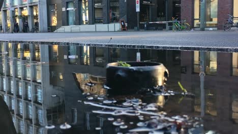 Gran-vereda-charco-de-lluvia-reflejando-tráfico-y-edificios