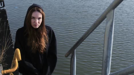 Young-Serious-Faced-Woman-Standing-on-River-Staircase