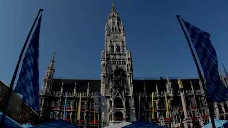 Clock-tower-im-Münchner-Marienplatz-umrahmt-von-bayerischen-flags