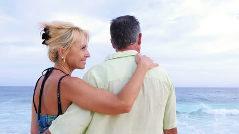 Close-up-of-an-older-couple-at-the-beach-with-their-arms-around-each-other-and-being-affectionate