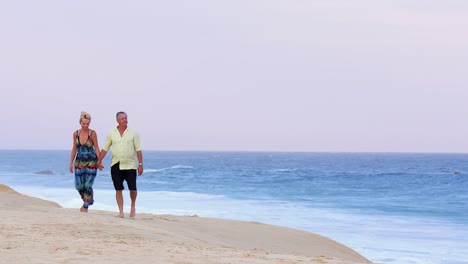 Eine-ältere-paar-Hände-halten,-zu-Fuß-am-Strand-entlang