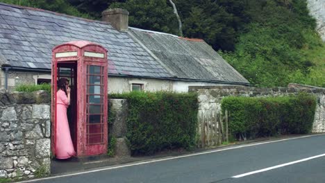 4k-Shot-of-a-Woman-posing-in-a-Red-Telephone-Box,-United-Kingdom