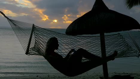 Frau-zum-Entspannen-in-der-Hängematte-am-Strand-und-unter-Handy-Fotos